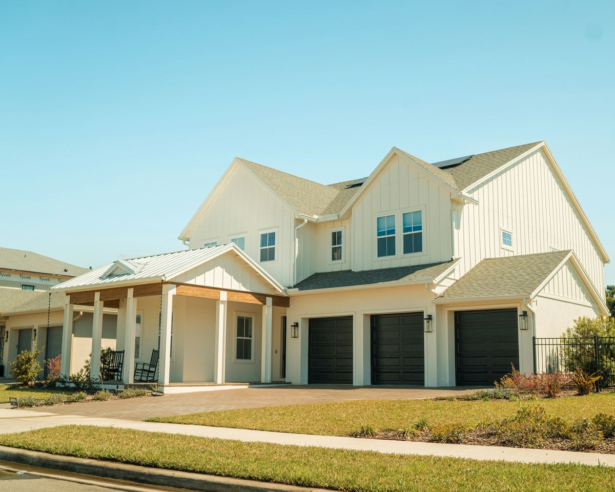 Newly built two-story Florida home with a covered front porch, three-car garage, and solar panels on the roof